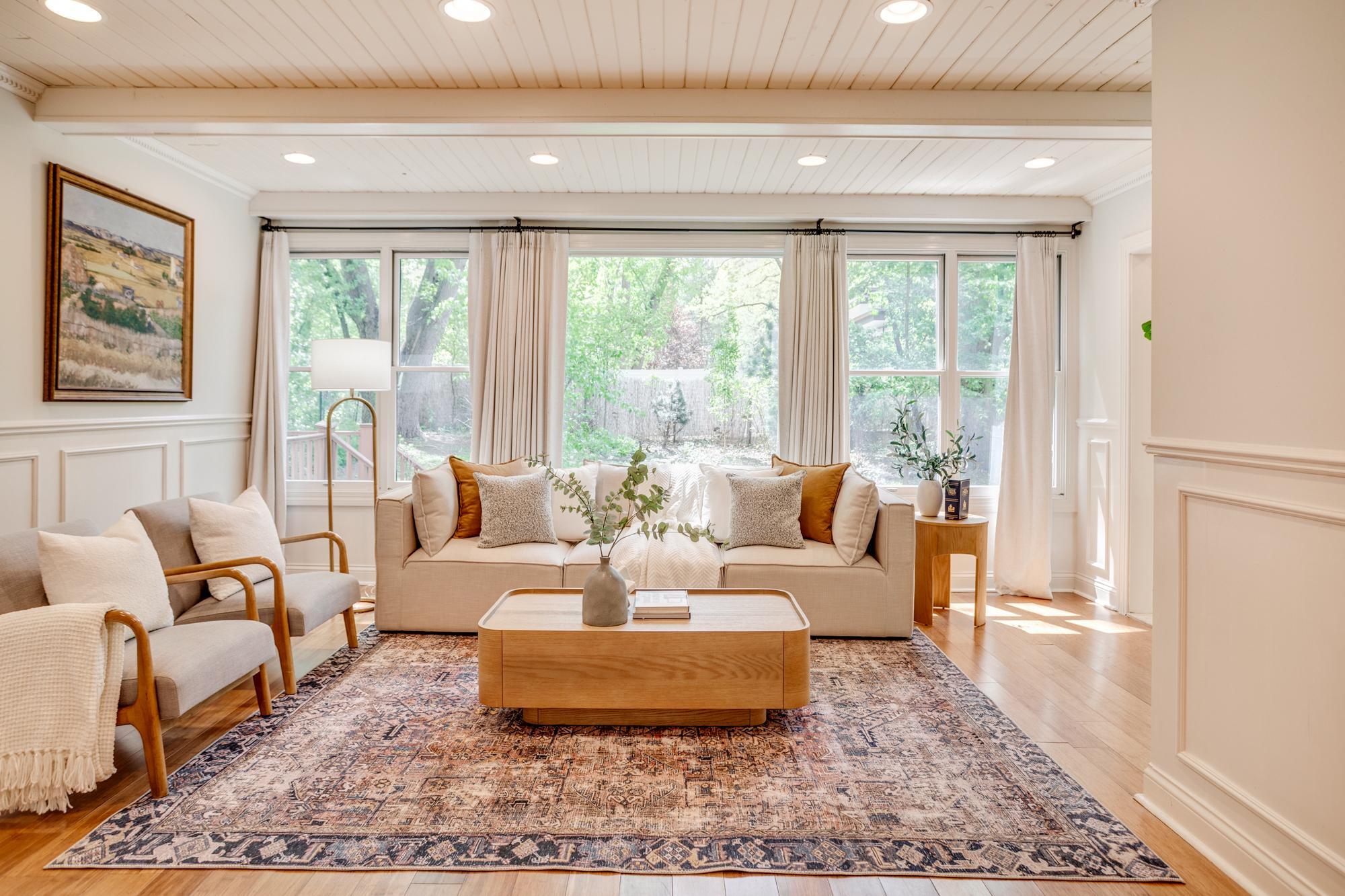 The spacious and bright family room features a beamed ceiling and a wall of windows overlooking the backyard.
