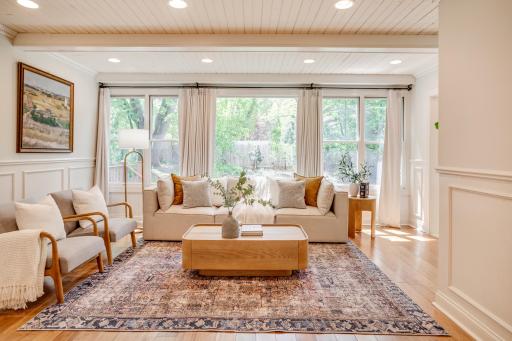 The spacious and bright family room features a beamed ceiling and a wall of windows overlooking the backyard.
