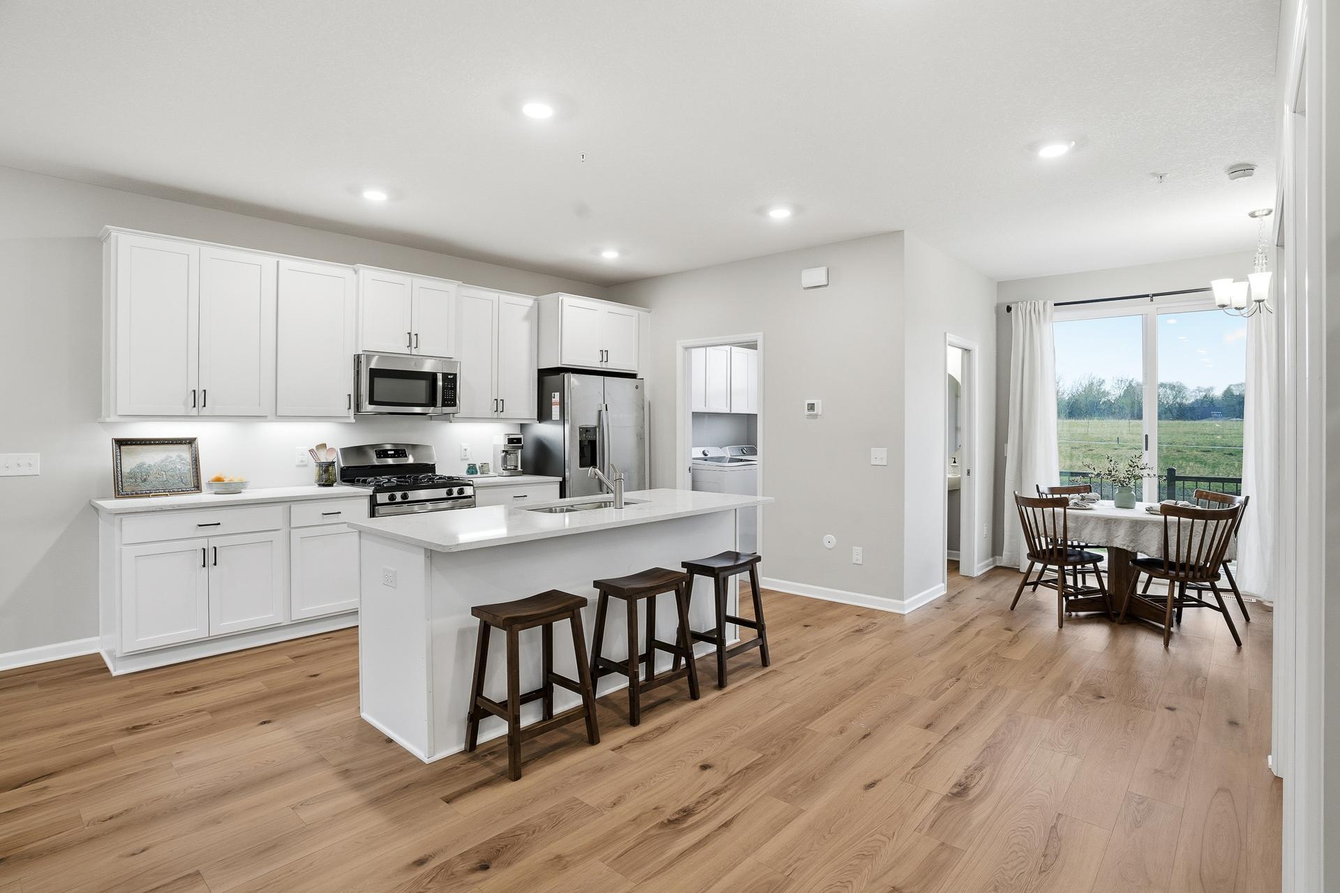 The stylish kitchen boasts stainless steel appliances, a gas range, bright quartz countertops, under cabinet lighting and a large island