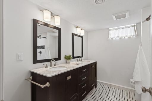 Updated lower-level 3/4 bathroom with dual sinks and walkout window.