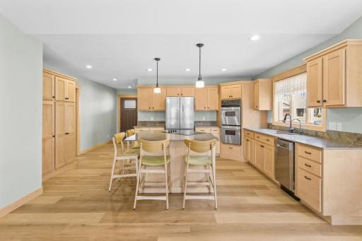 The generously-sized Kitchen features expansive Quartz countertops, a stylish slate tile backsplash, and custom Maple cabinets that boast plenty of storage.