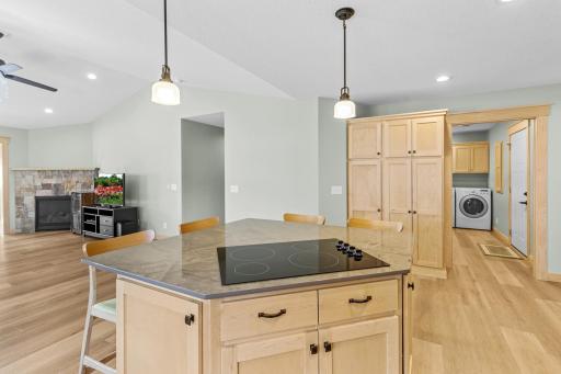 The upgraded island features elegant pendant lighting, a cooktop, additional seating, as well as an abundance of storage.