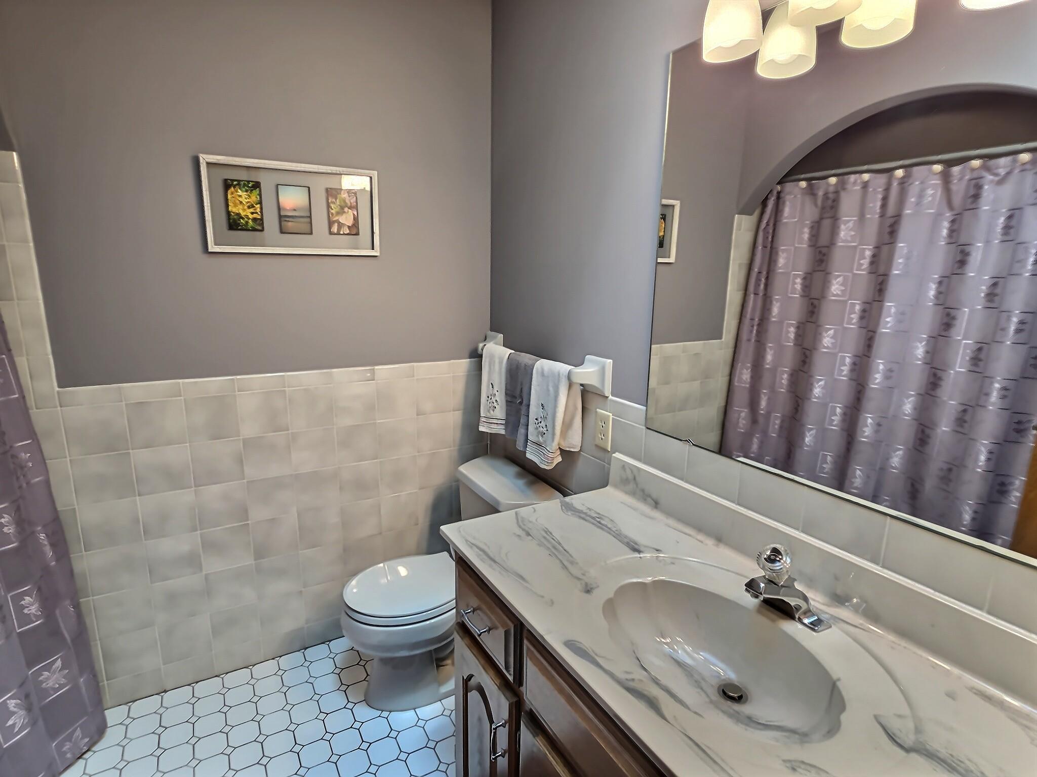 The upper-level bathroom is both charming and accommodating, featuring tile floors, a large vanity, and tub/shower combo. The skylight lets extra light in.