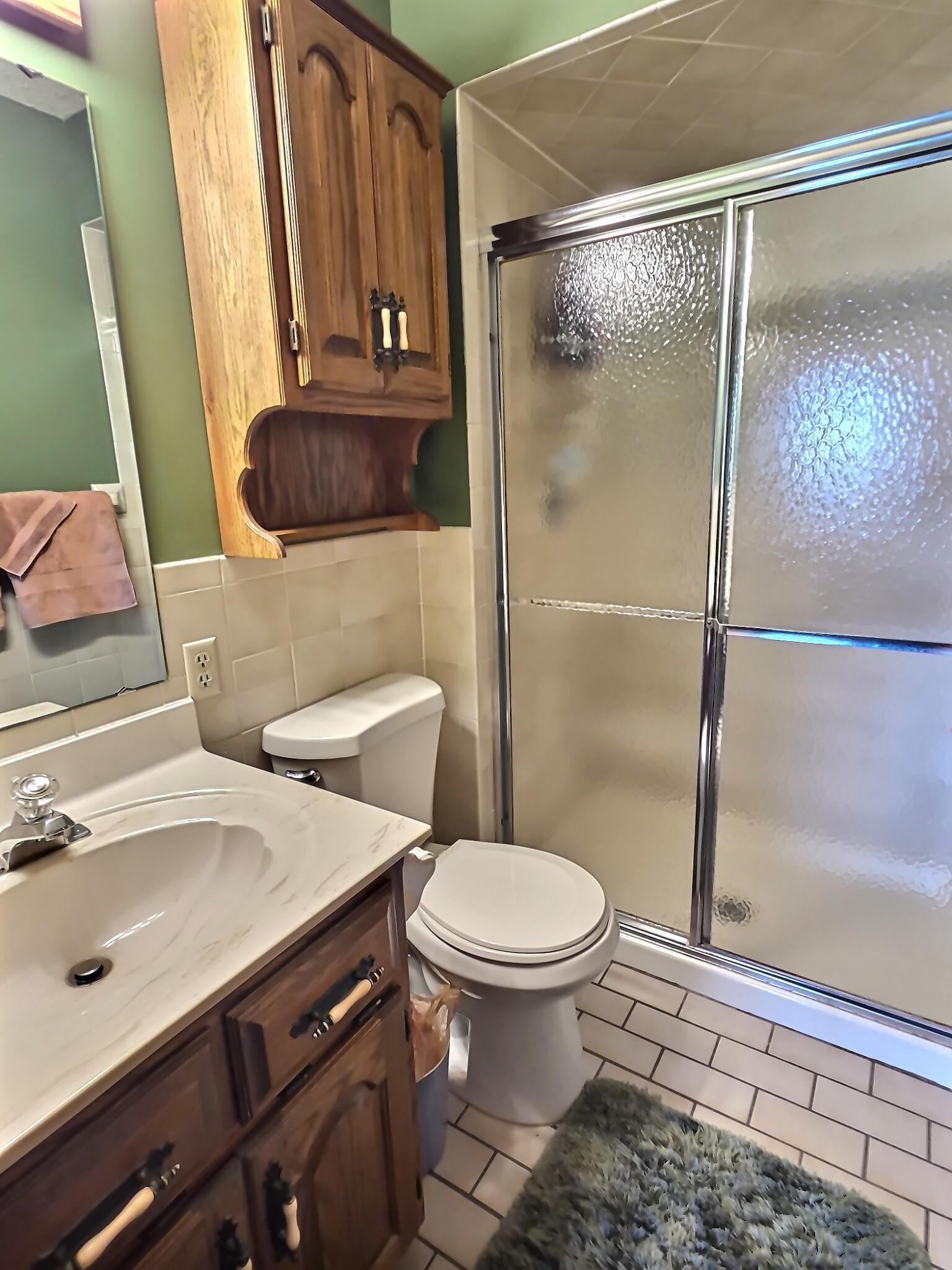 The 3/4 primary suite bathroom features crisp white tile flooring that creates a clean, bright, and timeless look. Brand new toilet as well!