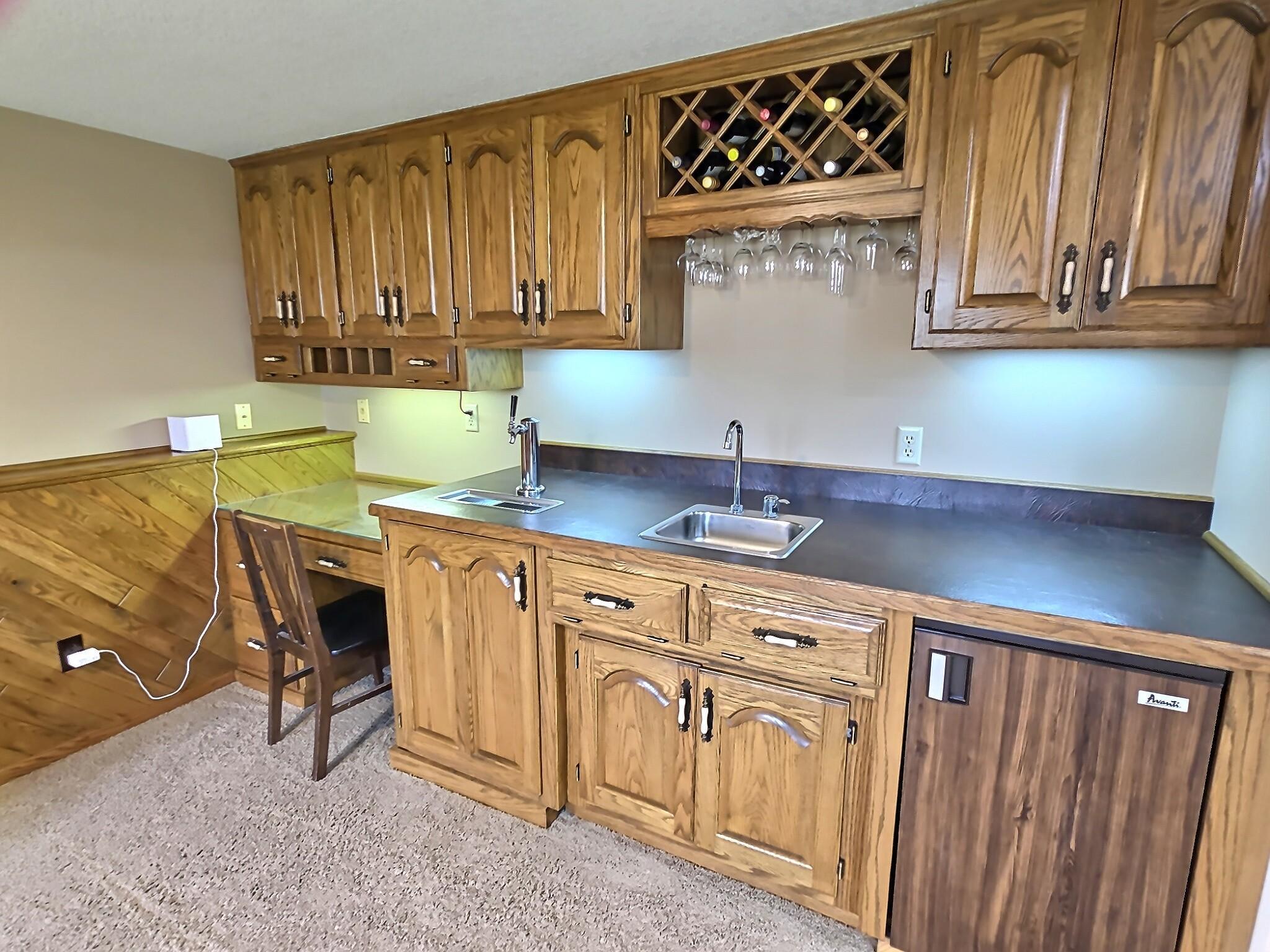 A thoughtfully designed built-in feature that combines a workspace, storage, and entertaining convenience in one seamless unit. Complete with a beer tapper, mini fridge, sink, glass holder, and bottle storage.
