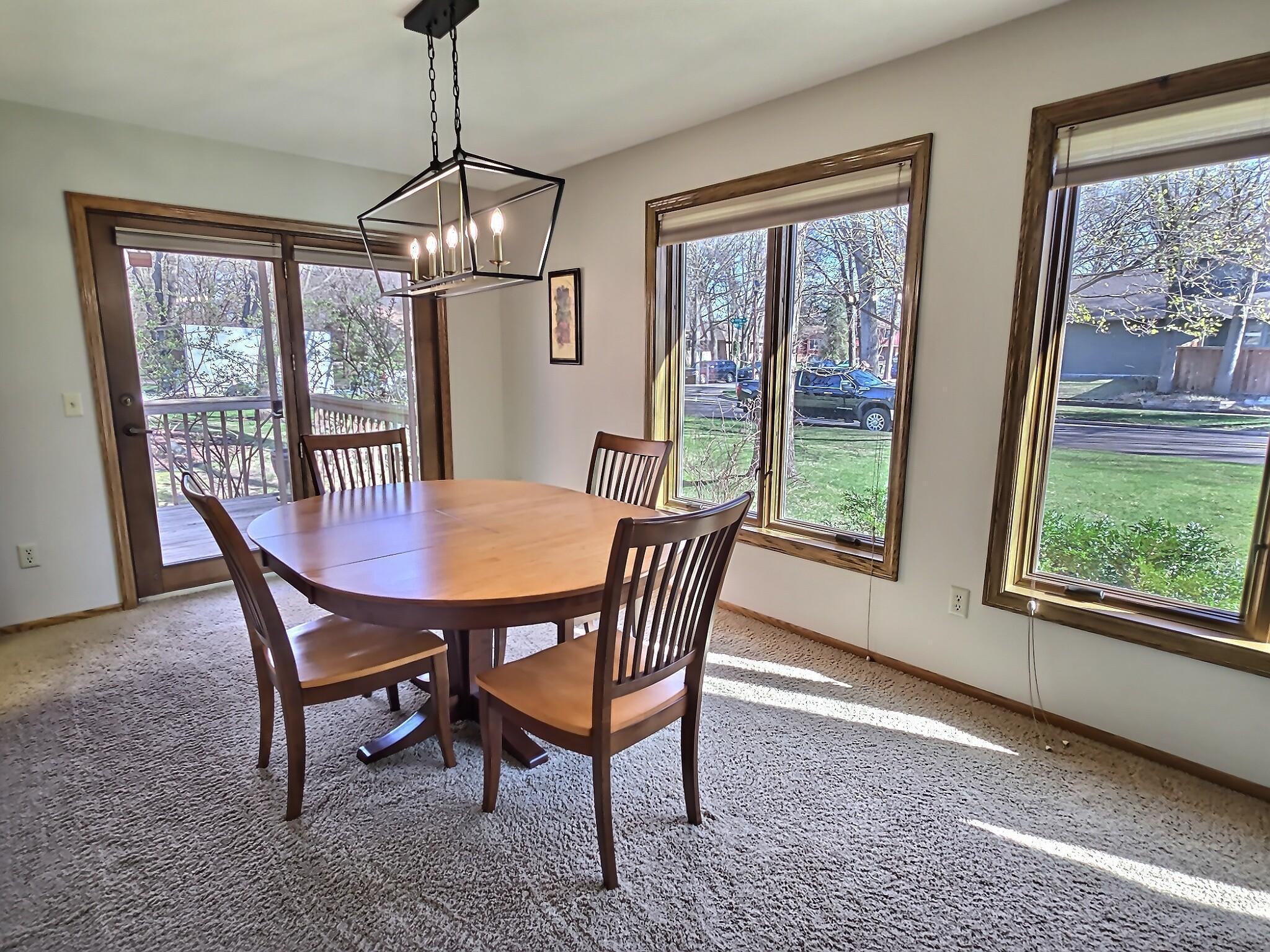 Surrounded by natural light, this roomy dining space features a new light fixture and transitions nicely to the deck.
