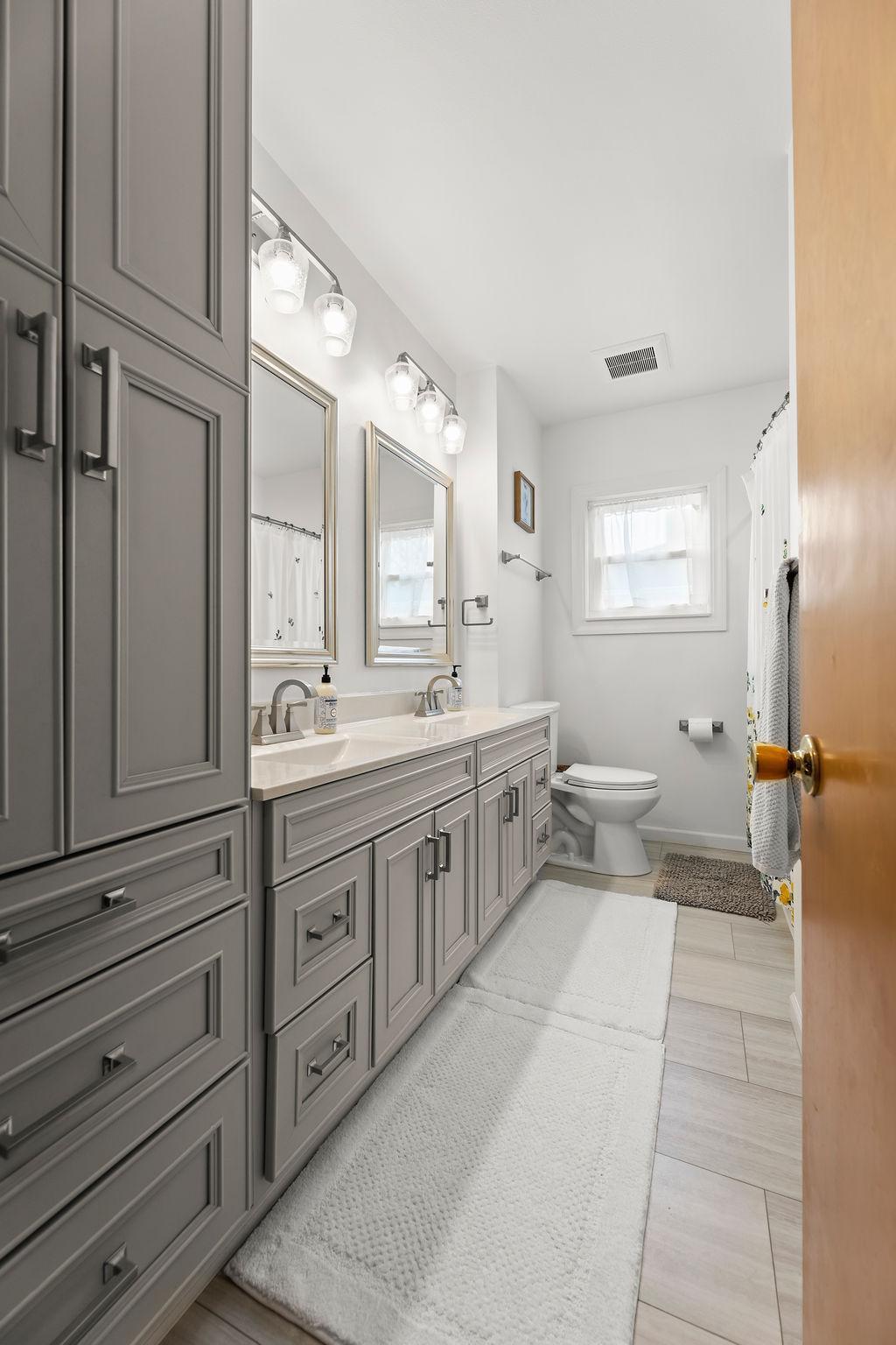 Main Floor Full Bathroom with double sinks & linen cabinet