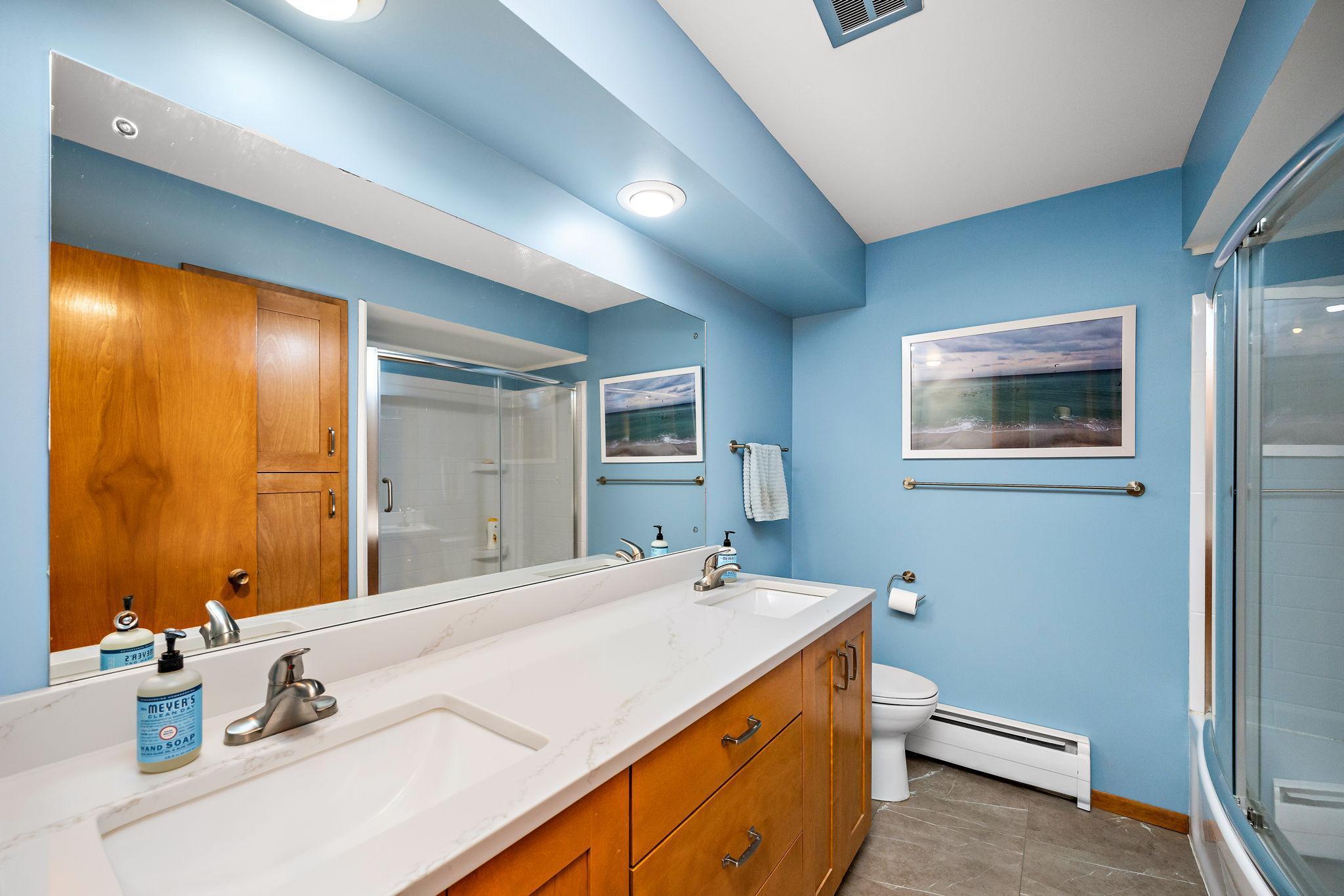Updated shared bath features a dual-sink adult-height vanity with soft-close doors and drawers and pull-out trays in the cabinets, tile floor, and linen closet!
