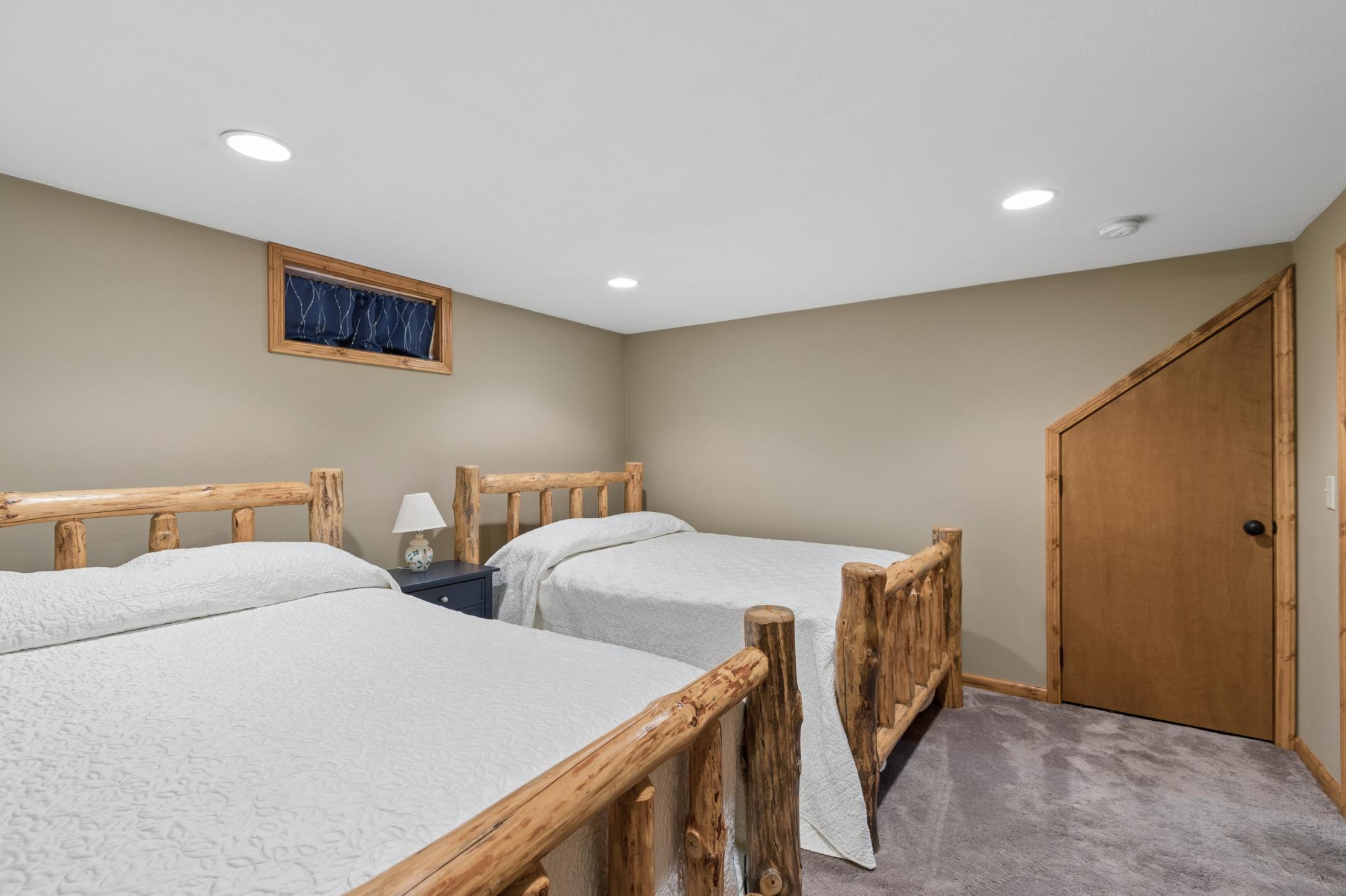View of the second lower-level bedroom with room for two queen size beds and a has an extra deep closet with storage running underneath the stairs. So often at the lake it isn't about how many bedrooms, but how many does it sleep.