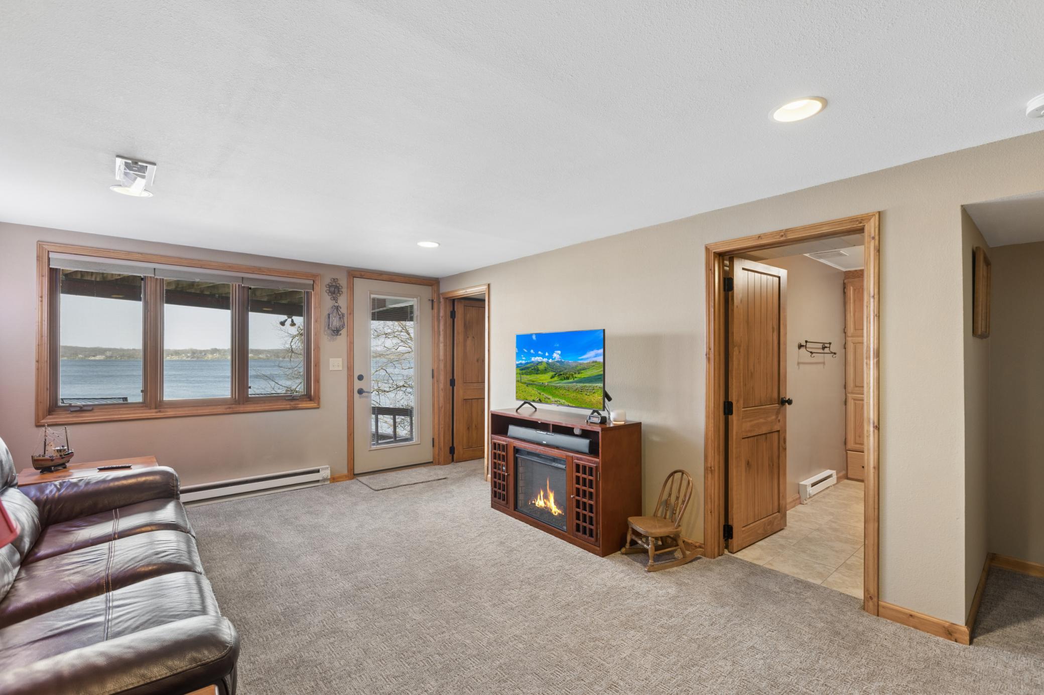 As we return inside the home to the walk-out lower level which features a spacious living room with large windows overlooking the lake.