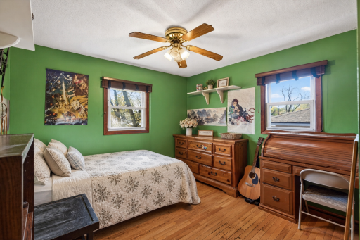 Second main level bedroom also featuring hardwood floors, dual windows, and a ceiling fan.
