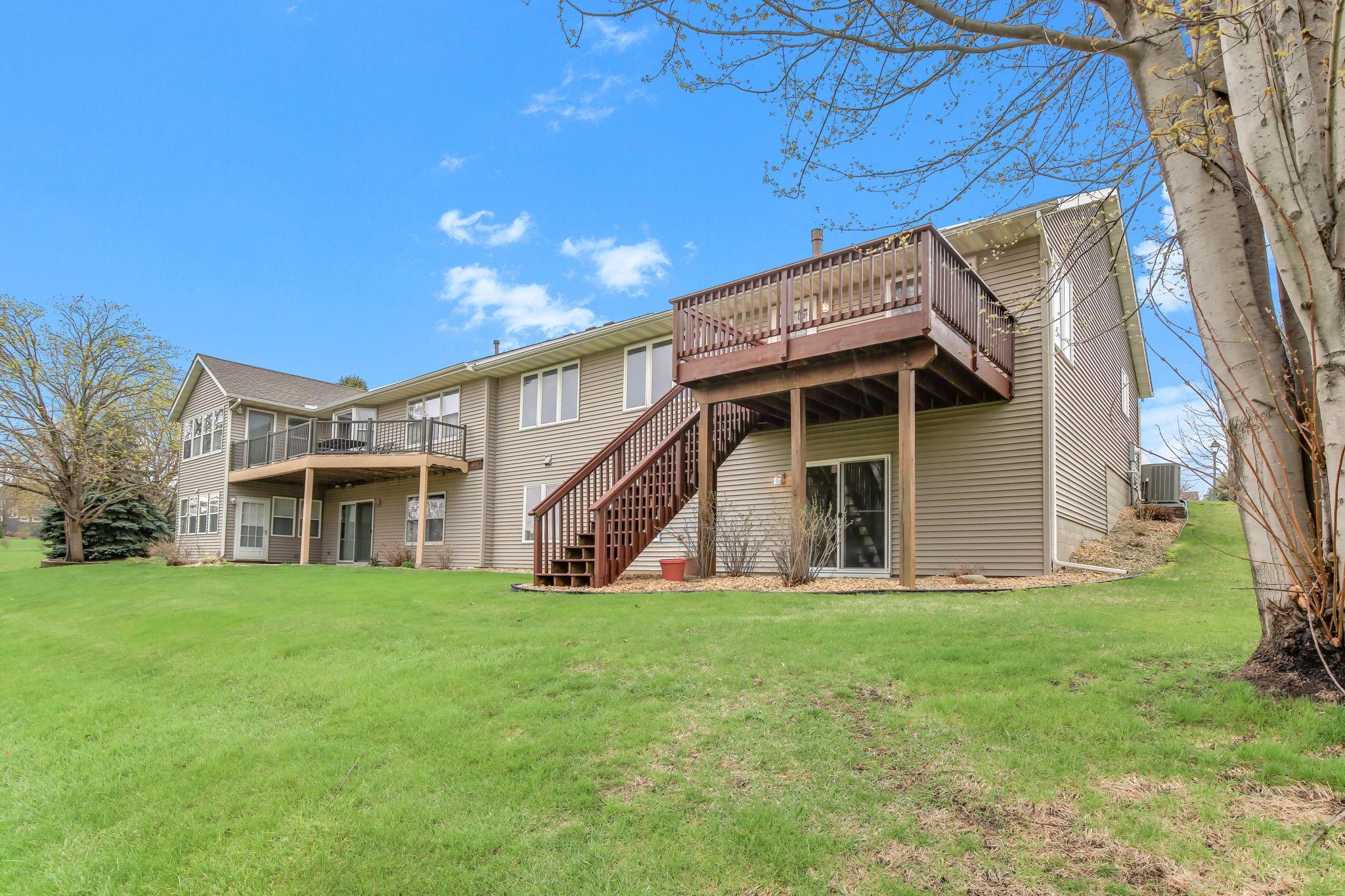 Deck off the great room with stairs down to the backyard and a walkout lower level patio—nice setup for enjoying the outdoors.