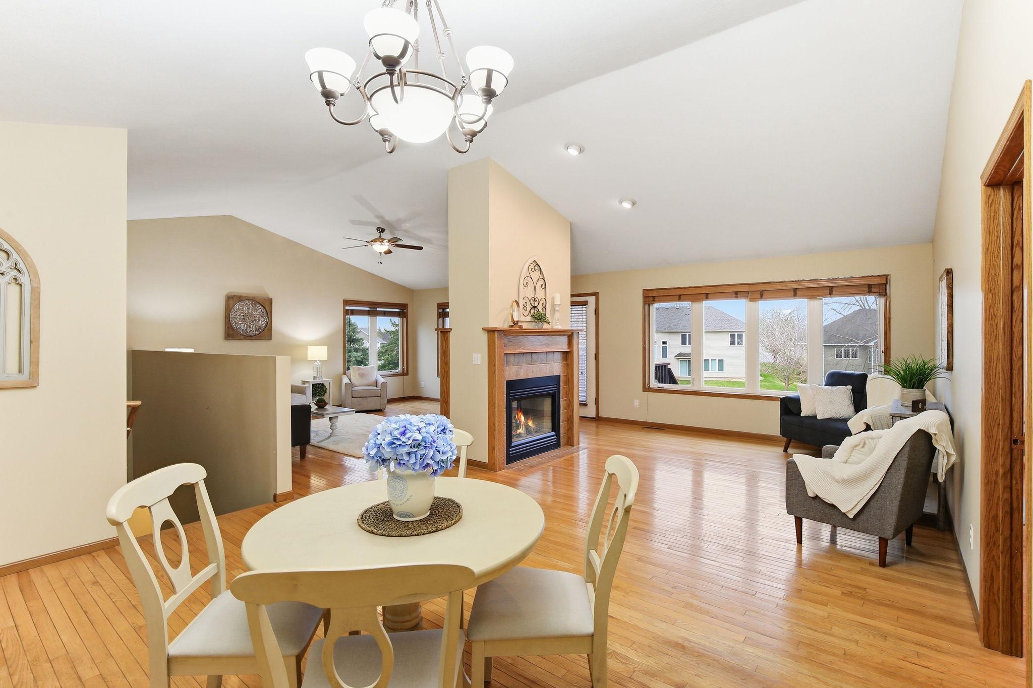 Spacious vaulted great room and dining area with hardwood floors and a see-through fireplace connecting the spaces.