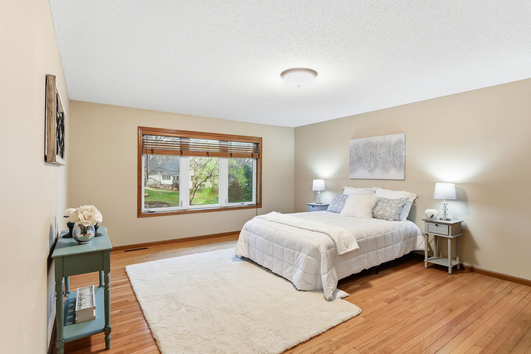 Extra-large main level primary bedroom with hardwood floors and plenty of space. It features a private bath and walk-in closet as well.
