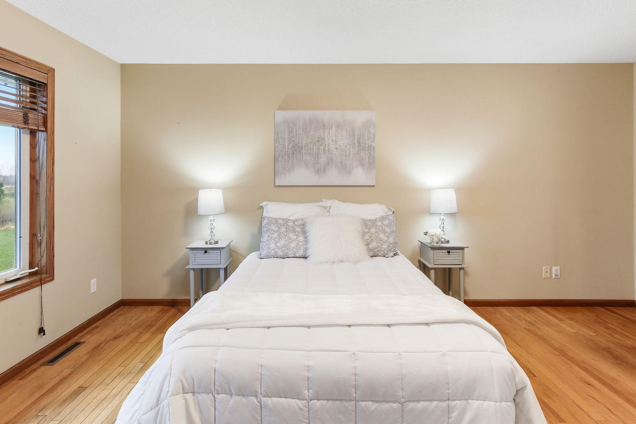 Extra-large primary bedroom on the main level with hardwood floors and space for a full furniture setup.