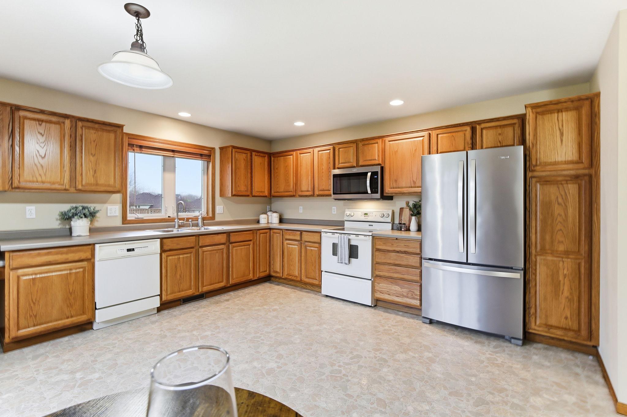 Large kitchen with extensive cabinet space, updated stainless steel refrigerator and microwave, and room for everyday use.
