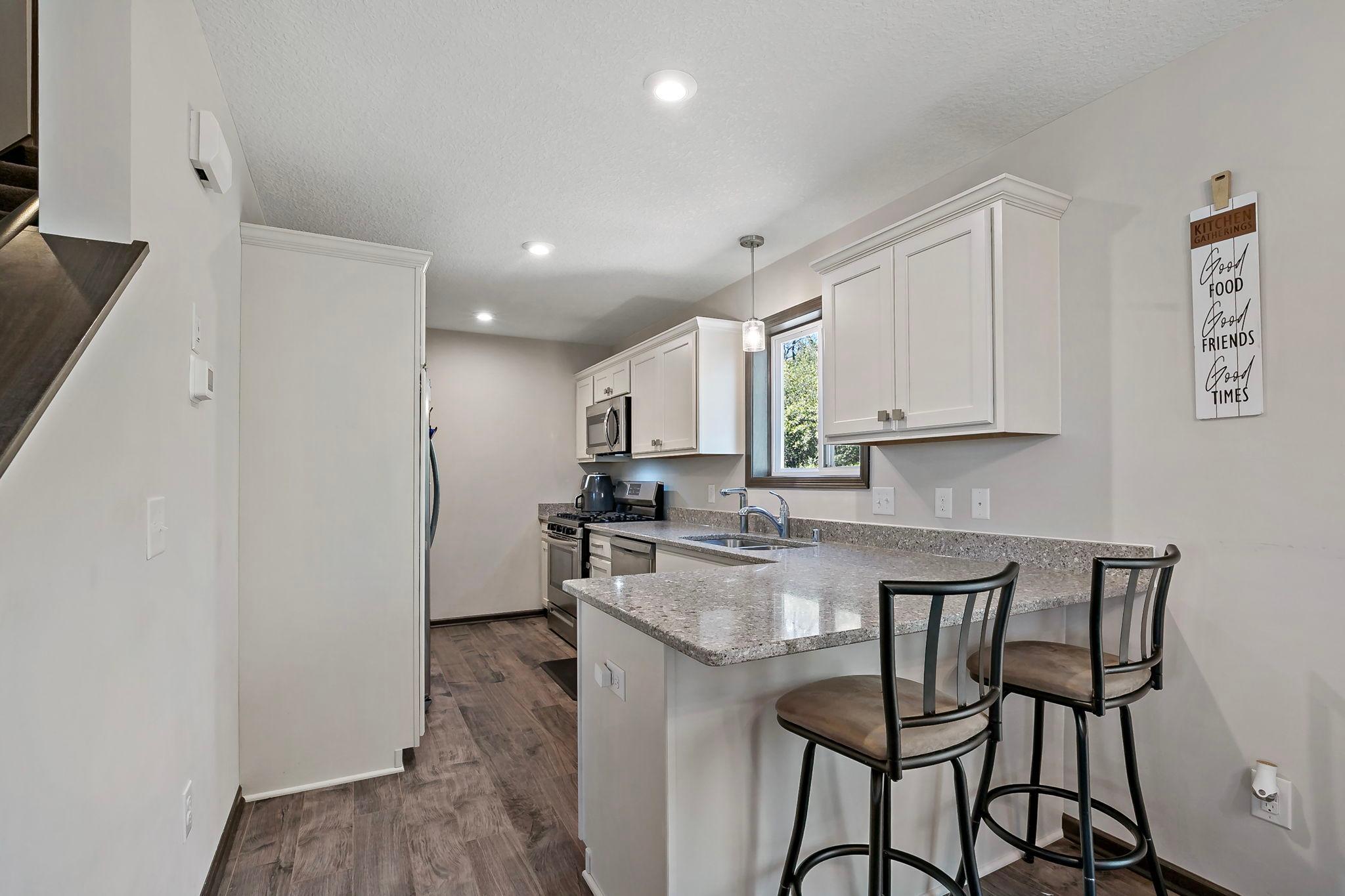 This kitchen features a range of desirable amenities, including counter seating, durable Silestone countertops, and abundant cabinetry with a dedicated pantry for added storage and organization.