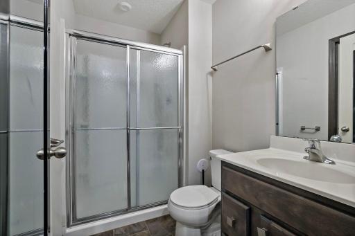 The lower-level 3/4 bathroom features a step-in shower with a glass door and durable LPV flooring, offering a clean, modern finish with easy maintenance.
