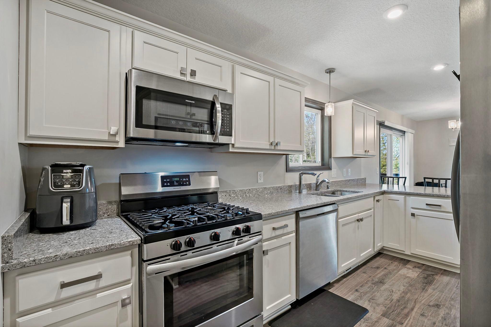The kitchen is well-appointed with a gas range, stainless steel appliances, and abundant natural light streaming through the kitchen window, creating a bright and functional space.