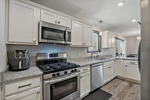 The kitchen is well-appointed with a gas range, stainless steel appliances, and abundant natural light streaming through the kitchen window, creating a bright and functional space.