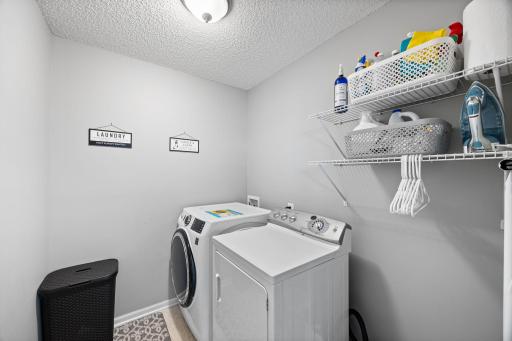 The upper-level laundry room, featuring a GE smart washer (2023), dryer, and built-in shelving, enhances daily routines.