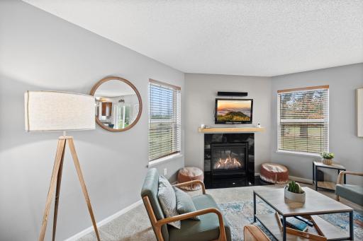 The living room feels comfortable and relaxed, featuring soft carpeting, a Heat-n-Glo fireplace, and large windows that bring in natural light and views of the backyard.