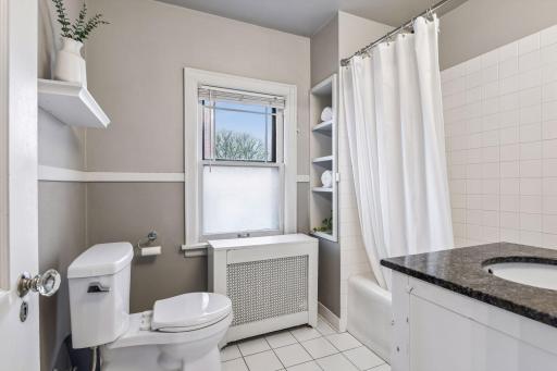 Clean and bright full bath with classic tile, natural light, and functional built-in storage for everyday ease