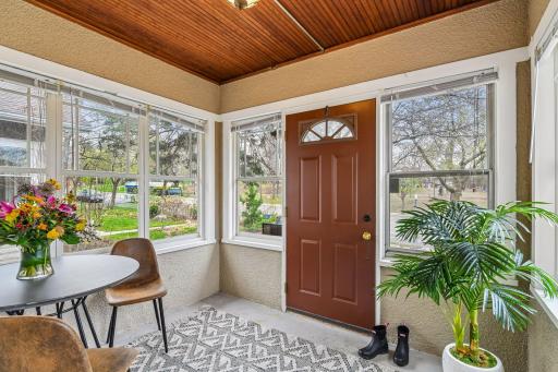 Bright enclosed front porch with natural light and charming wood ceiling detail