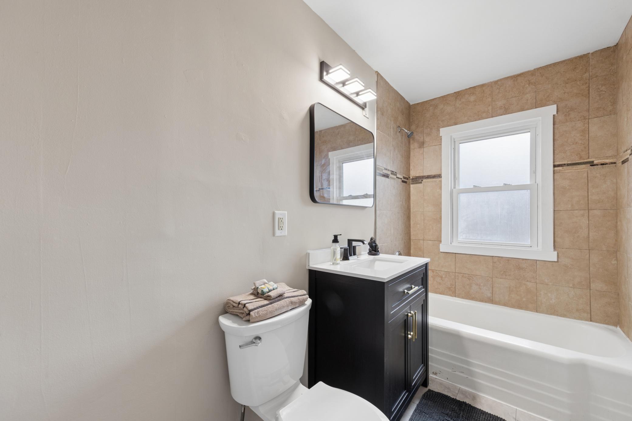 Updated full bathroom with modern vanity, tile surround, and clean, contemporary finishes.