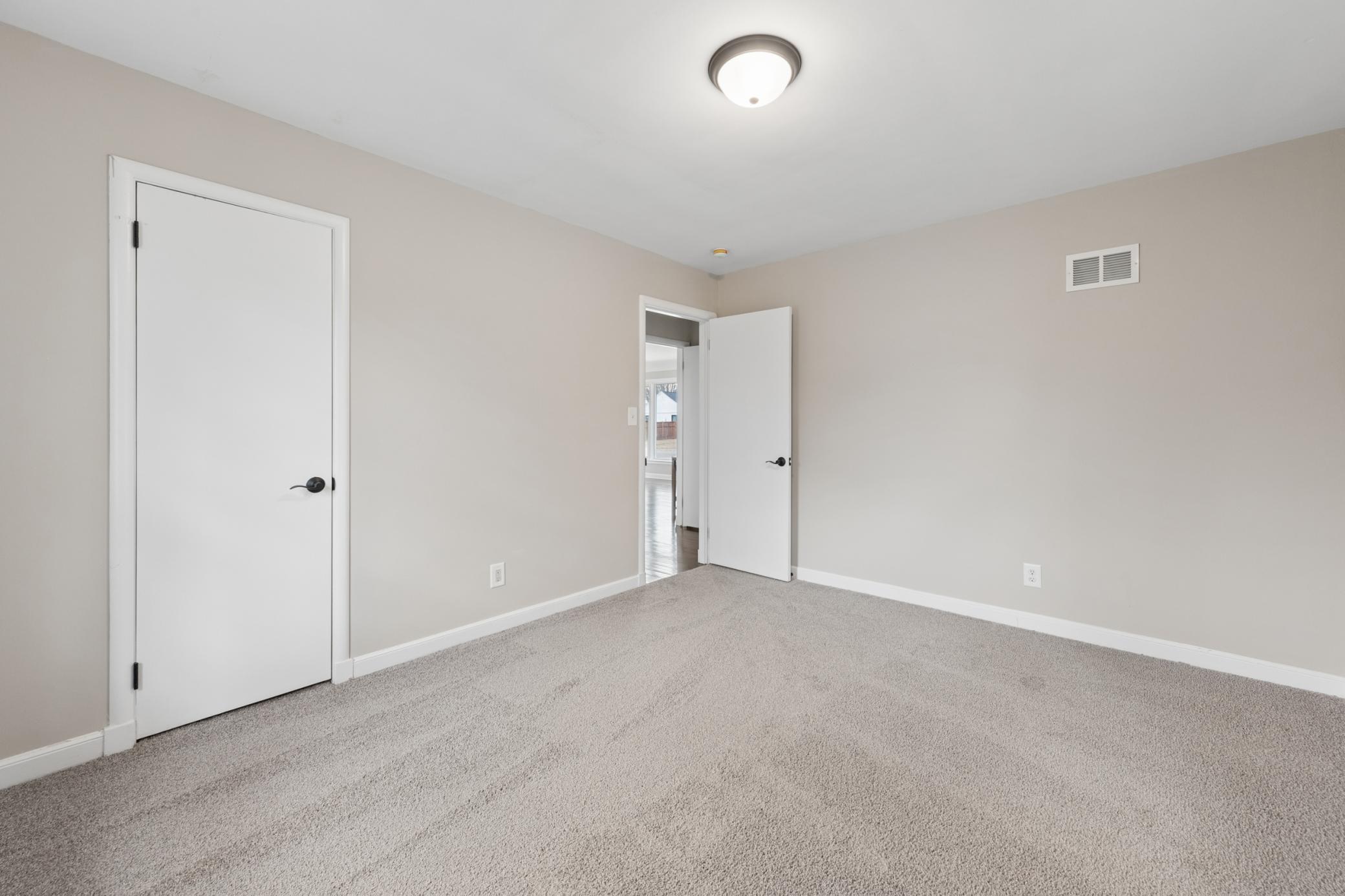 Additional bedroom featuring fresh carpet, neutral tones, and great natural light from multiple windows.