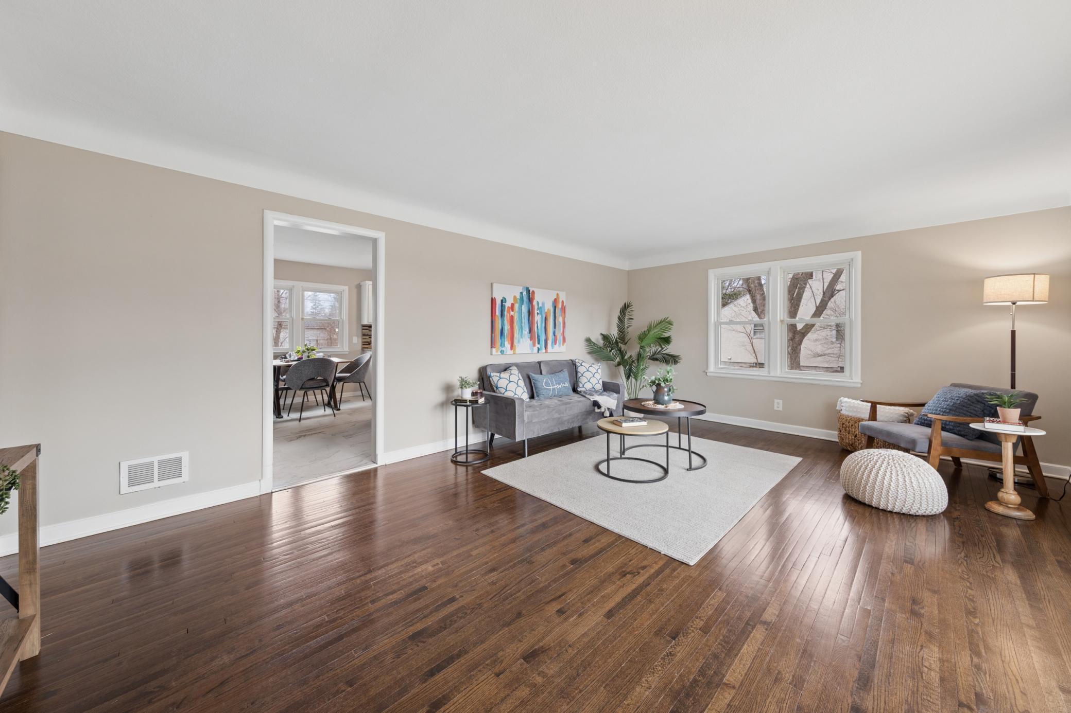 Spacious living room showcasing hardwood floors, large windows, and flexible layout for entertaining.