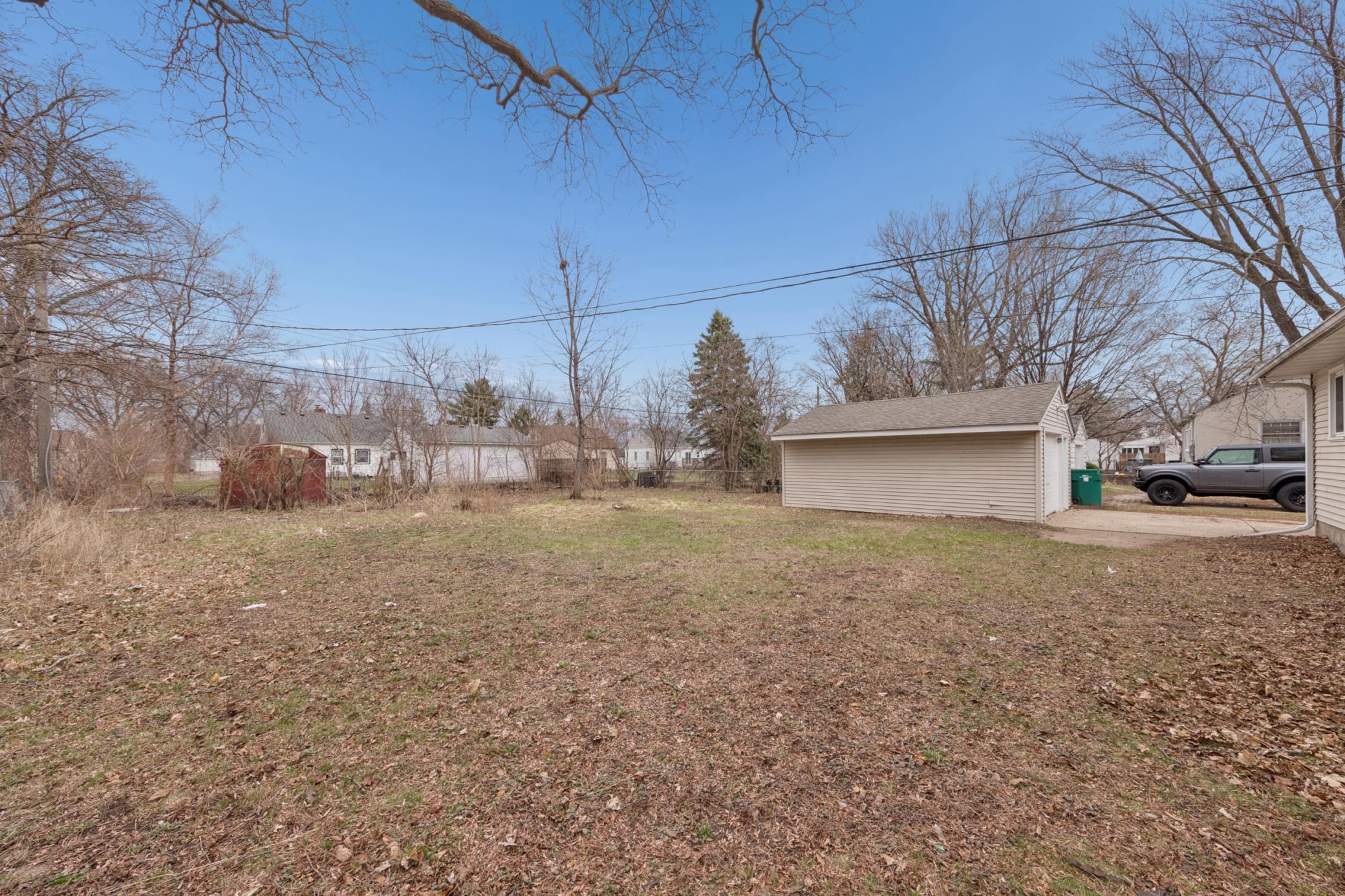 Backyard view showcasing detached garage, open green space, and room to expand or entertain.