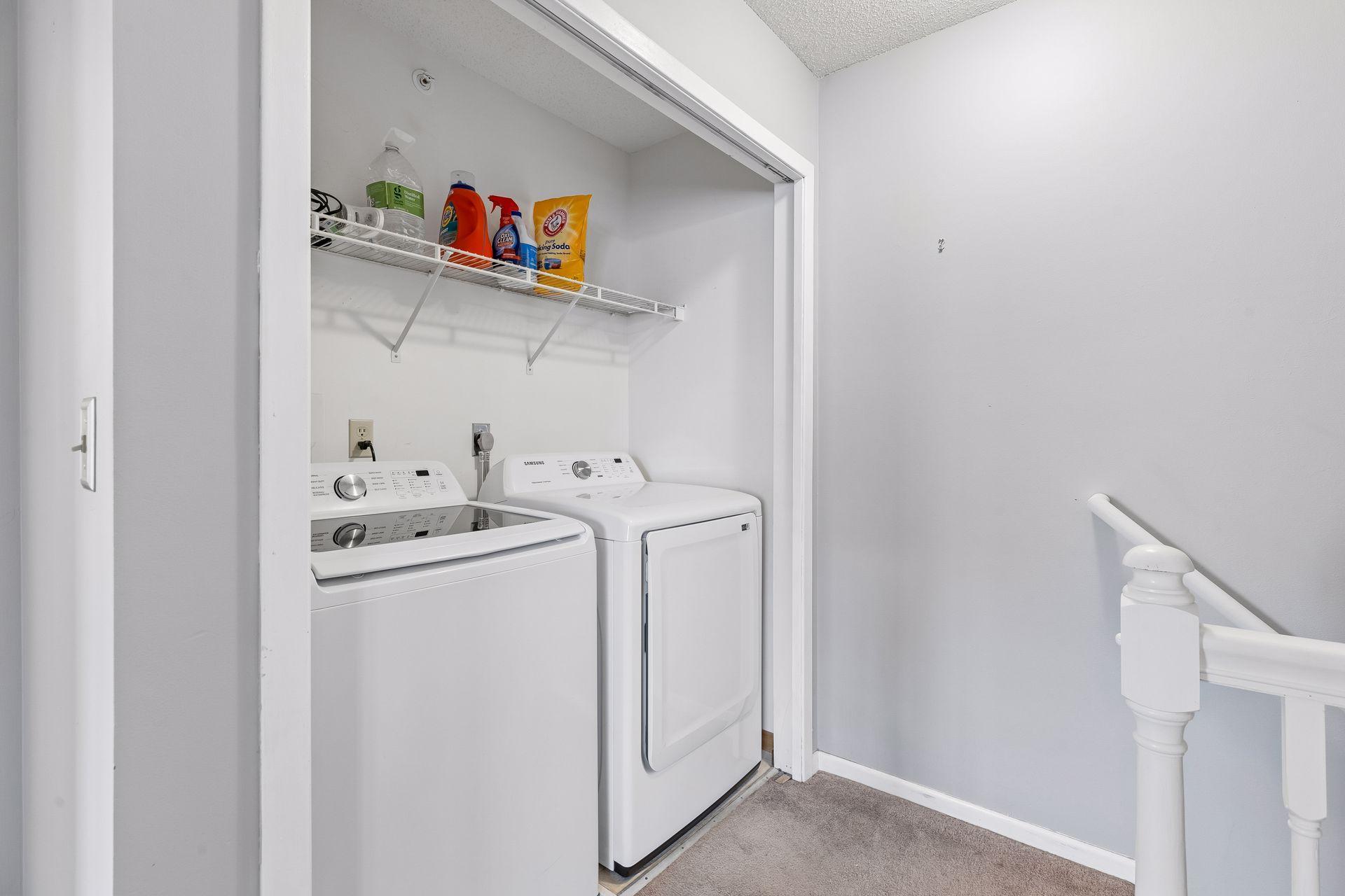 The large laundry closet features full-sized washer and dryer plus shelving for storage and hanging laundry to dry