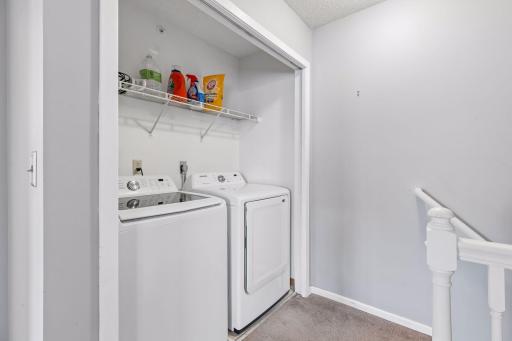 The large laundry closet features full-sized washer and dryer plus shelving for storage and hanging laundry to dry