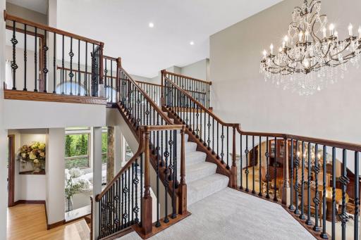 An elegant staircase illuminated by a stunning chandelier creates a breathtaking first impression filled with timeless sophistication.