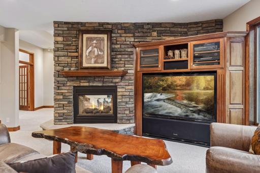 The see-through stone surround fireplace elegantly connects the recreation room and the sophisticated sitting area