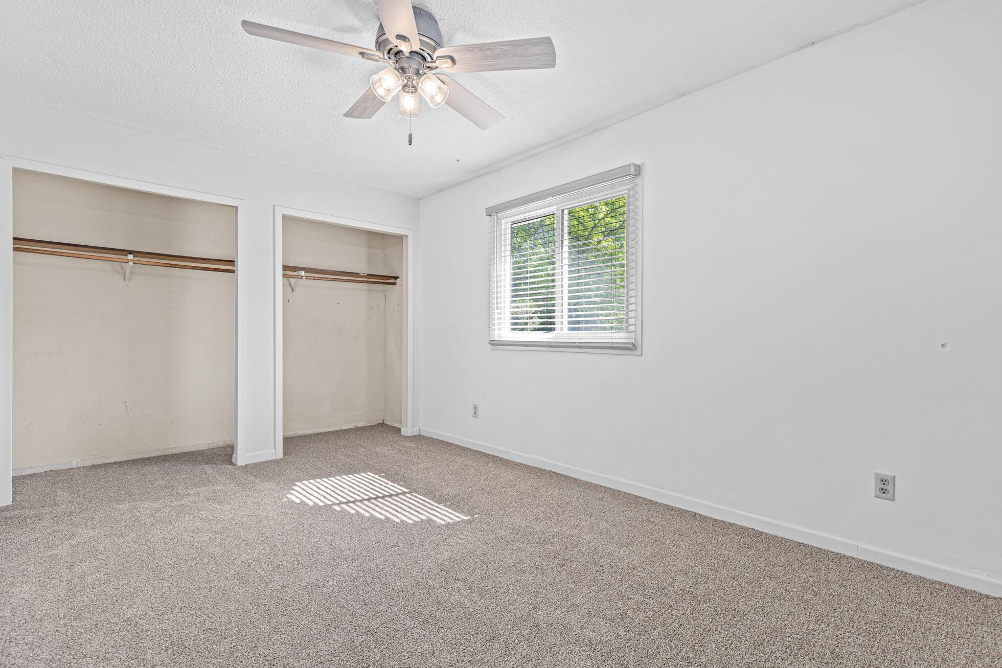 Second upper level bedroom with a neutral palette and ceiling fan for added comfort.