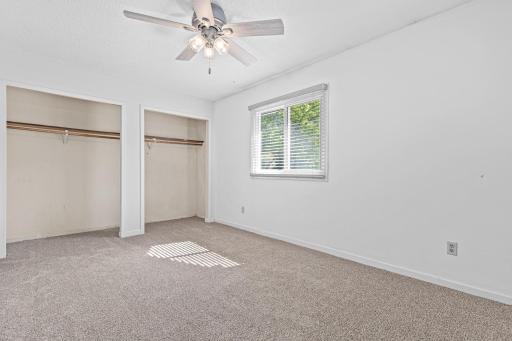 Second upper level bedroom with a neutral palette and ceiling fan for added comfort.