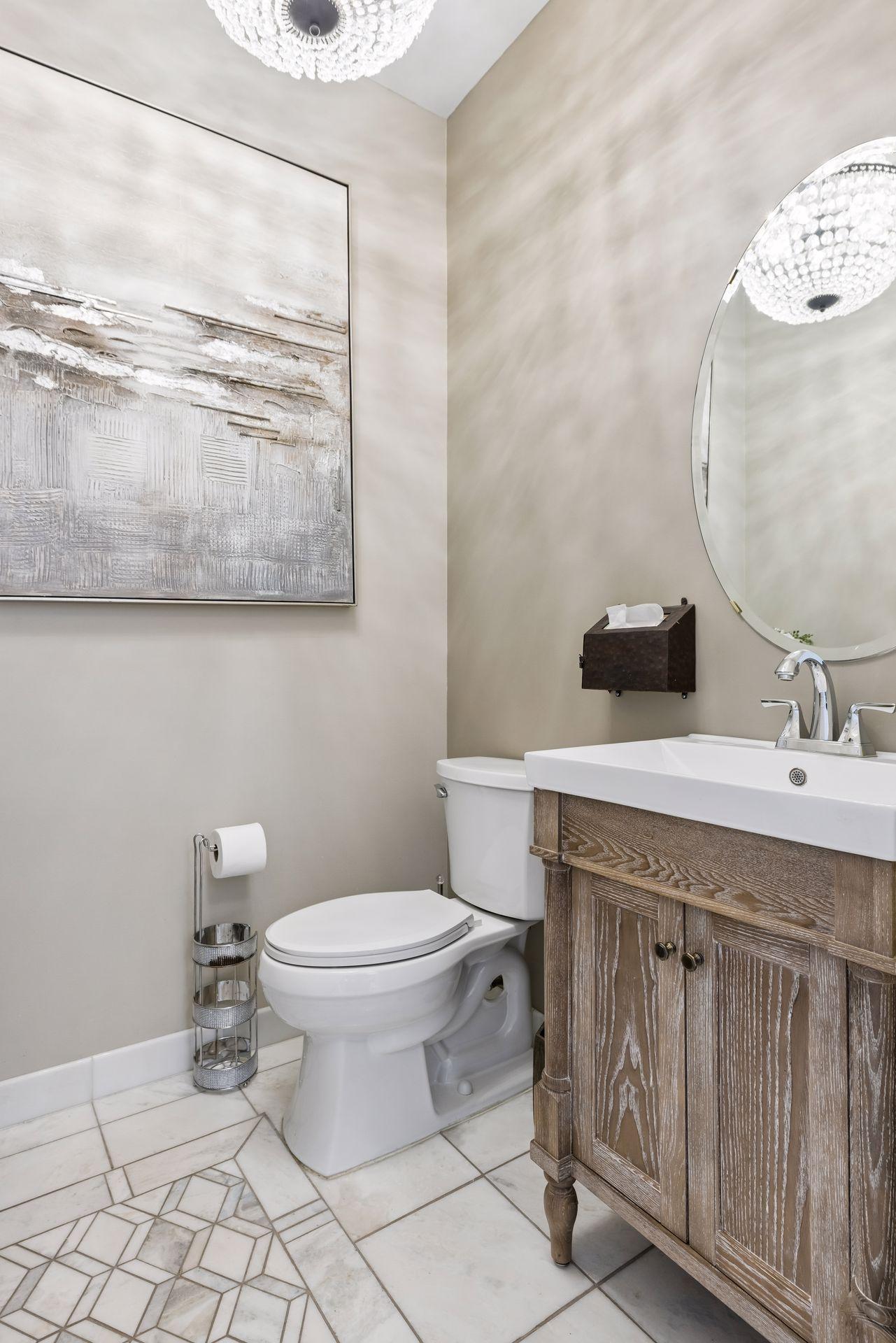 Main floor half bath with updated vanity, Marble-look porcelain tile with decorative inlay detail.