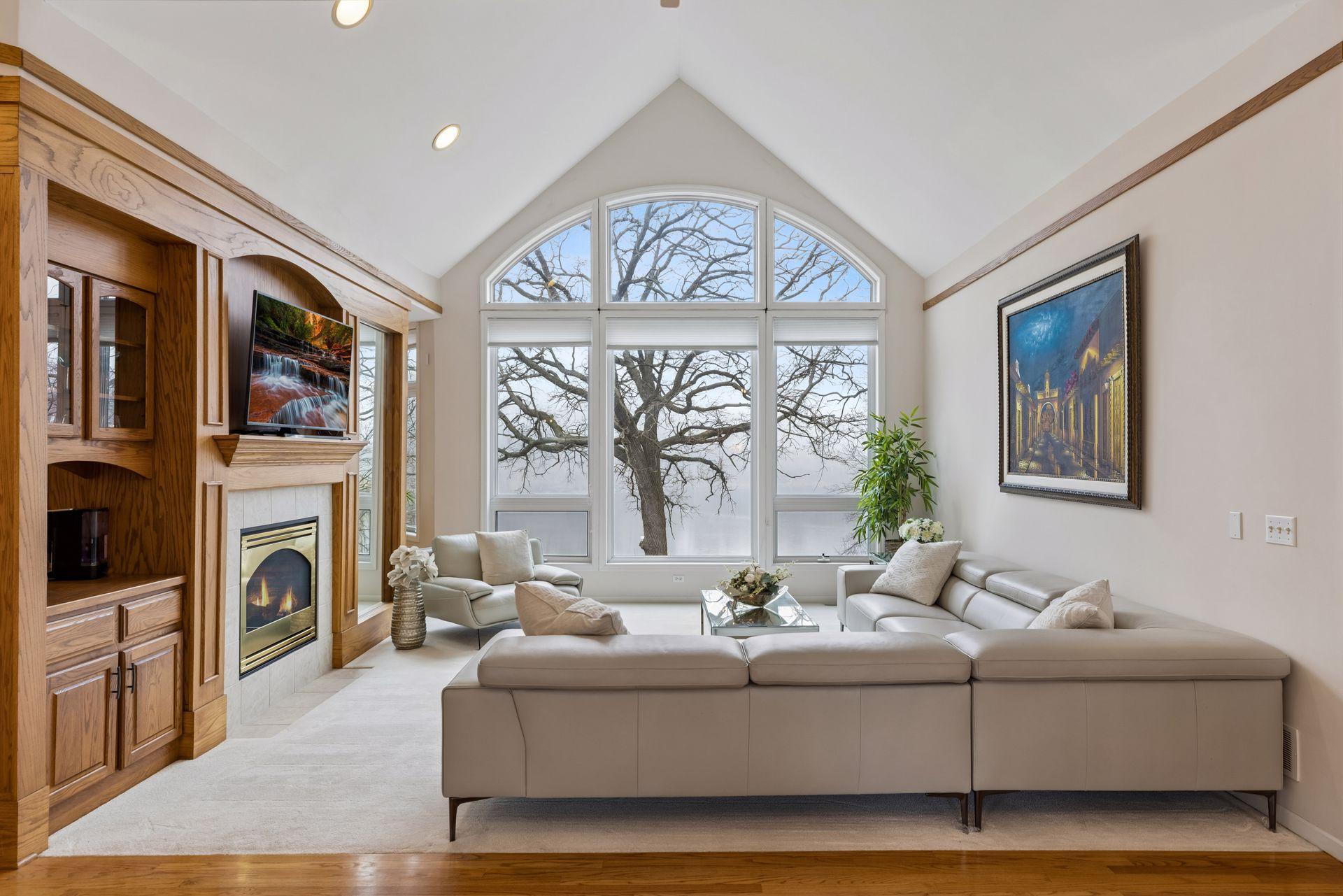 A stunning focal point of the home, this light-filled living room showcases dramatic vaulted ceilings and an impressive wall of windows that frame serene views of Karth Lake.