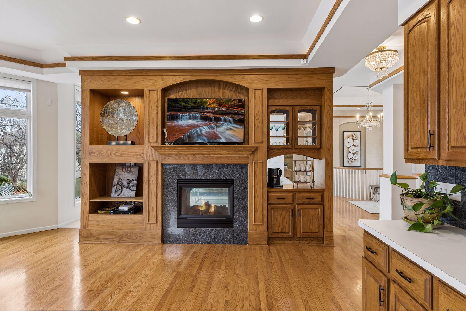 Perfectly positioned within the open-concept layout, this custom built-in entertainment center showcases rich woodwork and timeless design. The inviting fireplace is framed seamlessly into the surrounding living and kitchen space.