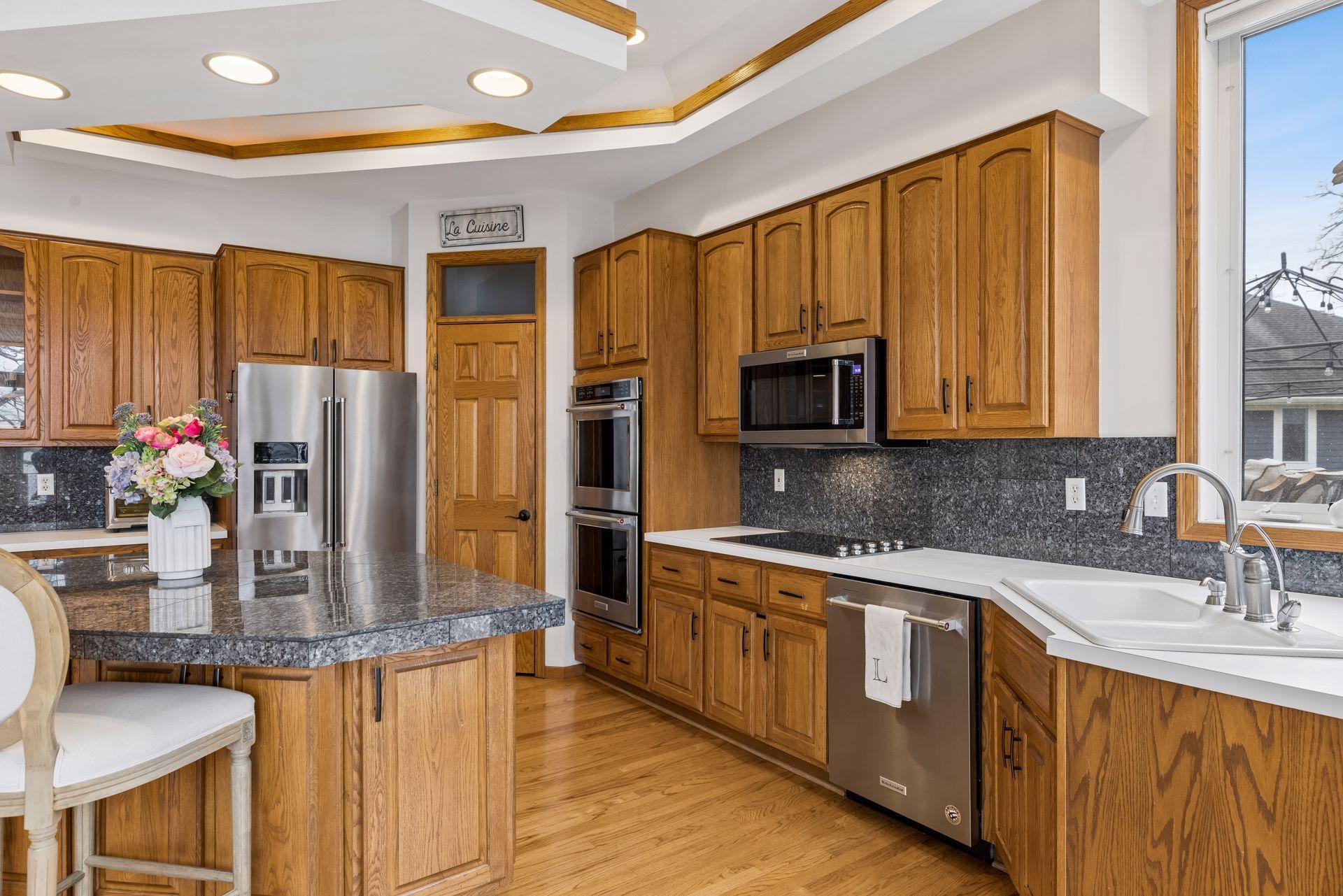 High ceilings with elegant tray detailing add an elevated touch, while stainless appliances and abundant storage make this kitchen as functional as it is inviting.