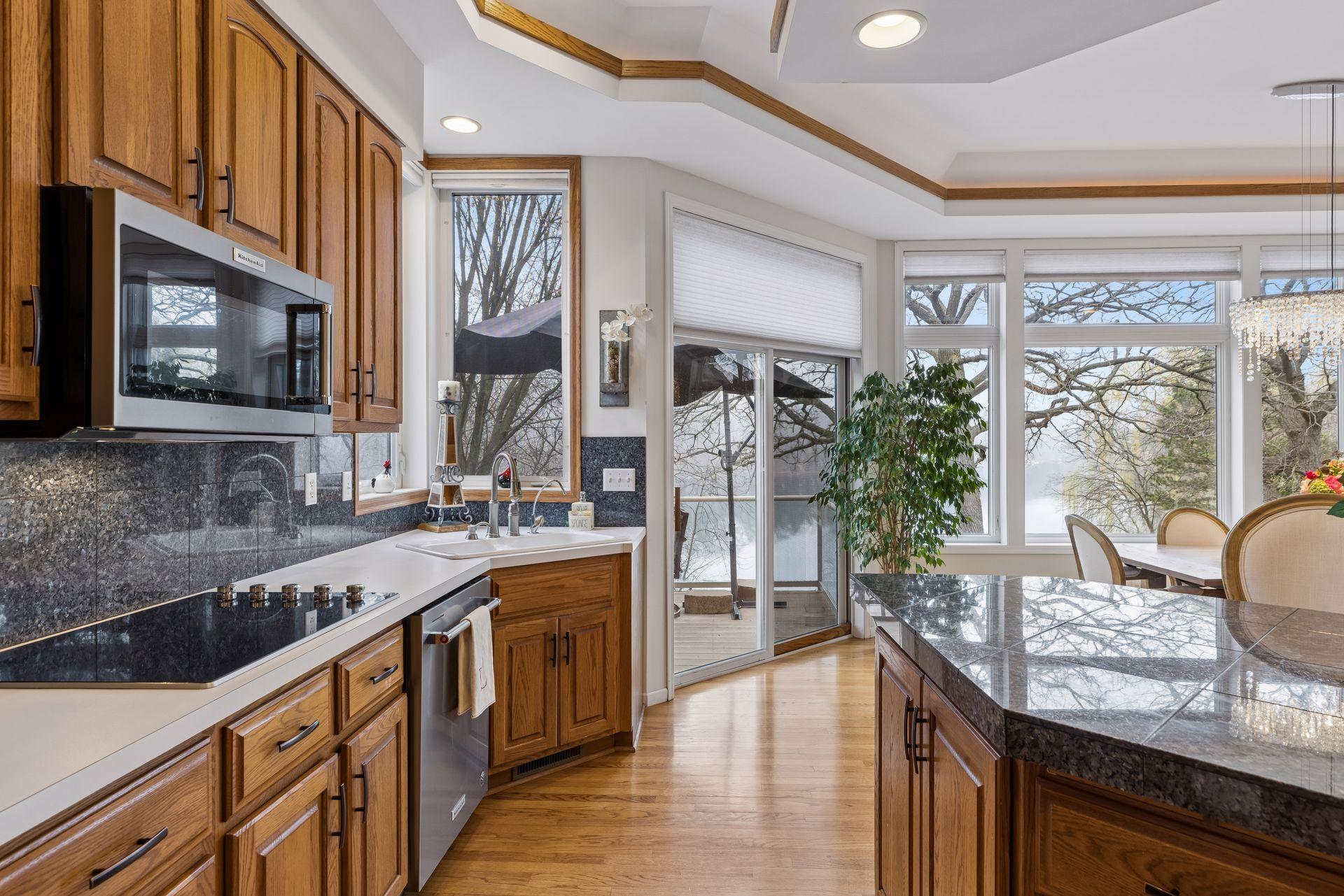 Sun-filled gourmet kitchen overlooking the water! This beautifully maintained kitchen features warm hardwood cabinetry, sleek granite backsplash, and an upgraded cooktop with microwave.