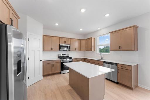 The stylish kitchen includes a walk-in pantry, beautiful ceramic tile backsplash, and a full suite of stainless steel appliances.