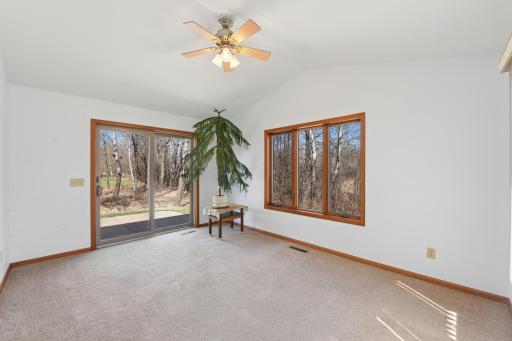 The sunroom offers a sliding glass door to the patio surrounded by views of nature