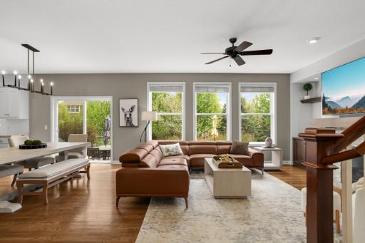 Rich hardwood flooring flows throughout the home, complemented by oversized windows that flood the space with natural light and a walkout to the patio for seamless indoor-outdoor living.