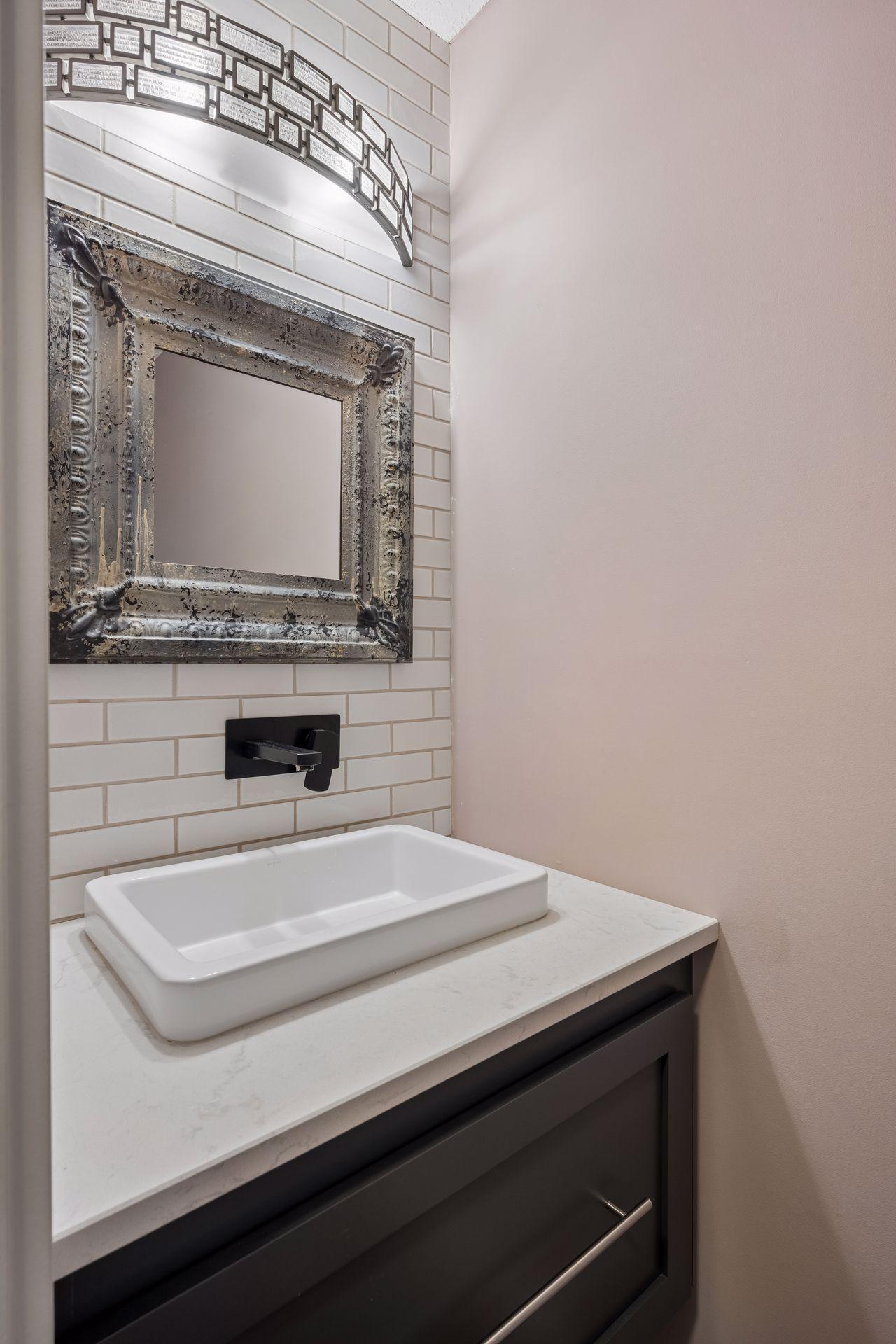 New quartz vanity with floating sink, tile backasplah and designer mirror