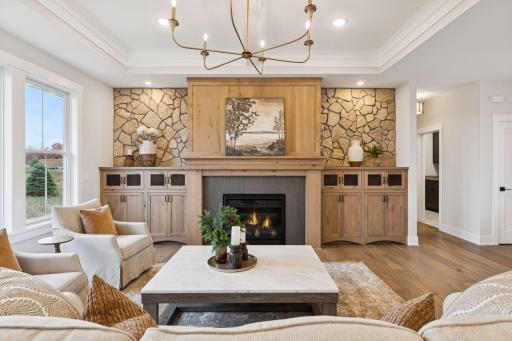 Warm and inviting living room with gas fireplace custom built-ins, and stone accents