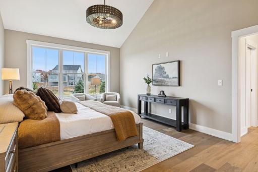 Vaulted ceiling paired with a bold, modern chandelier creates a spacious and stylish focal point in the primary bedroom