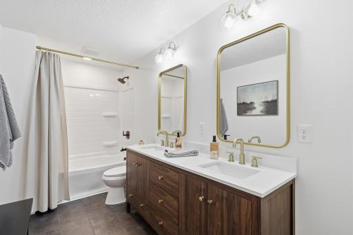 Lower level bathroom recently finished with dual sink vanity, tile floors, white tub/surround. Convenient space for a bench.